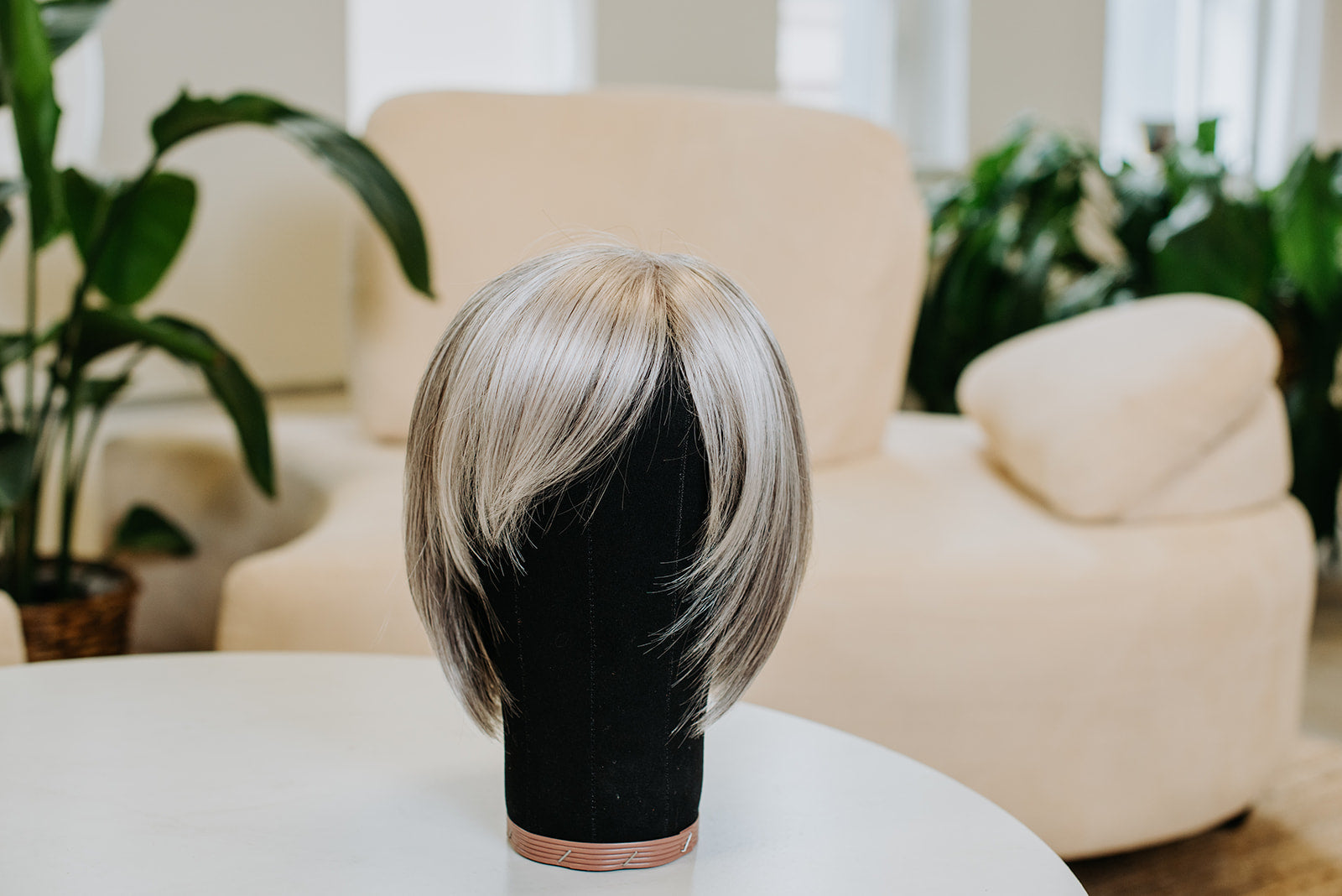 A short, blonde wig on a wig stand.