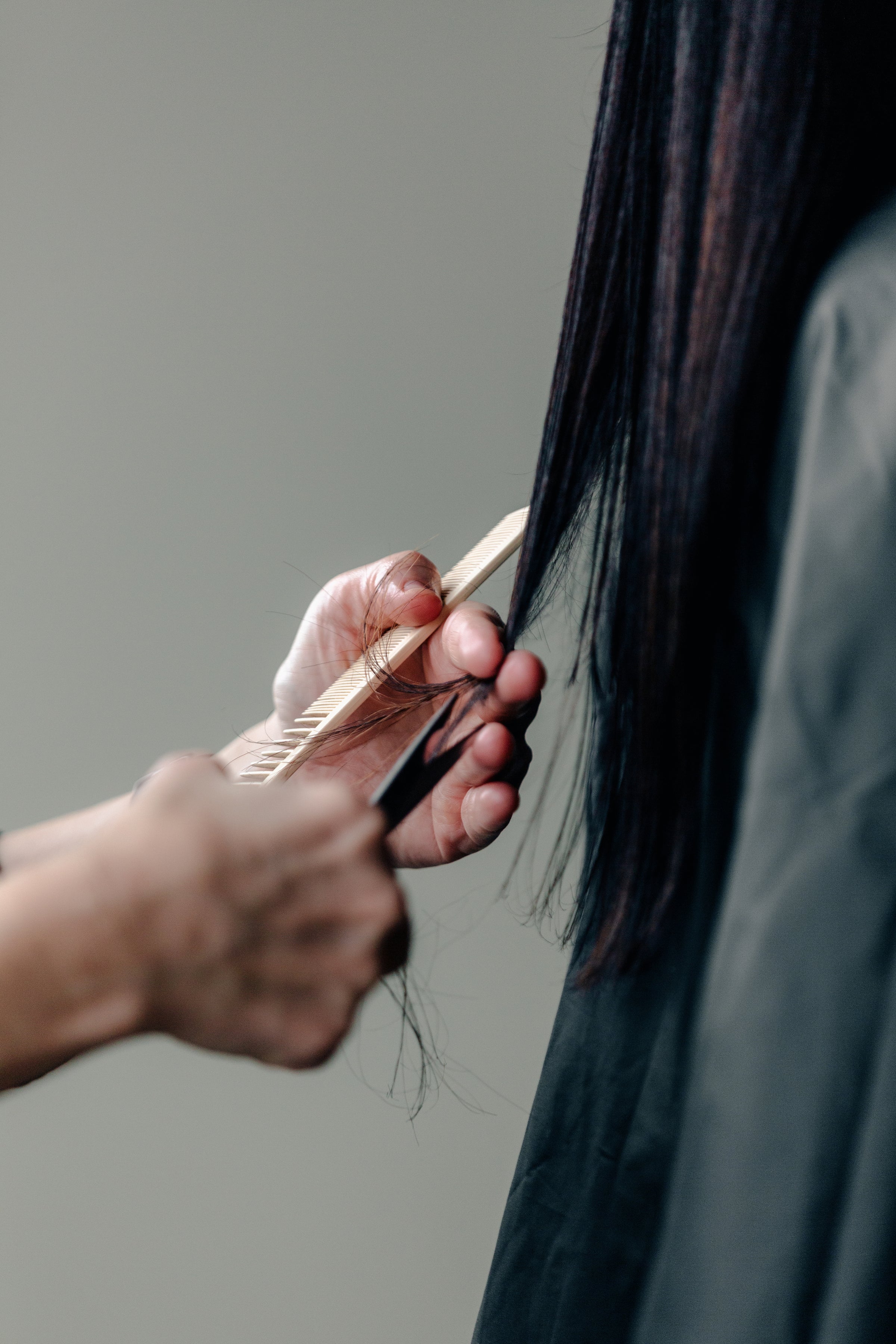 Hair stylist cutting long, black hair.